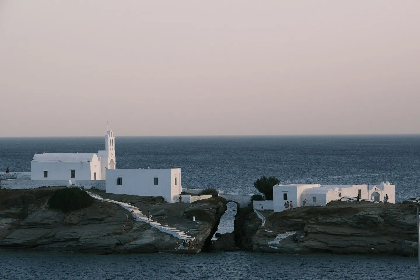 Whitewashed church and buildings on a rocky outcrop above the sea at dusk, Sifnos