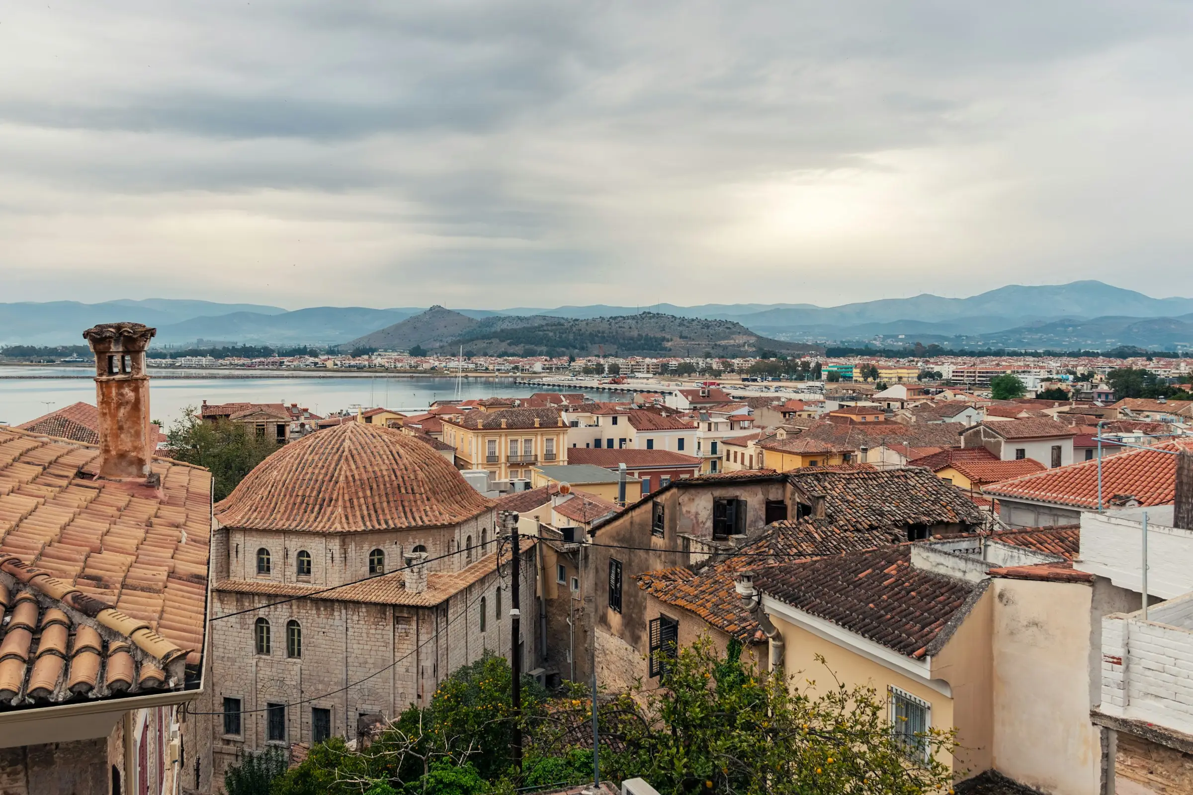 Terracotta rooftops and a domed stone church overlooking the bay and hills of Nafplio