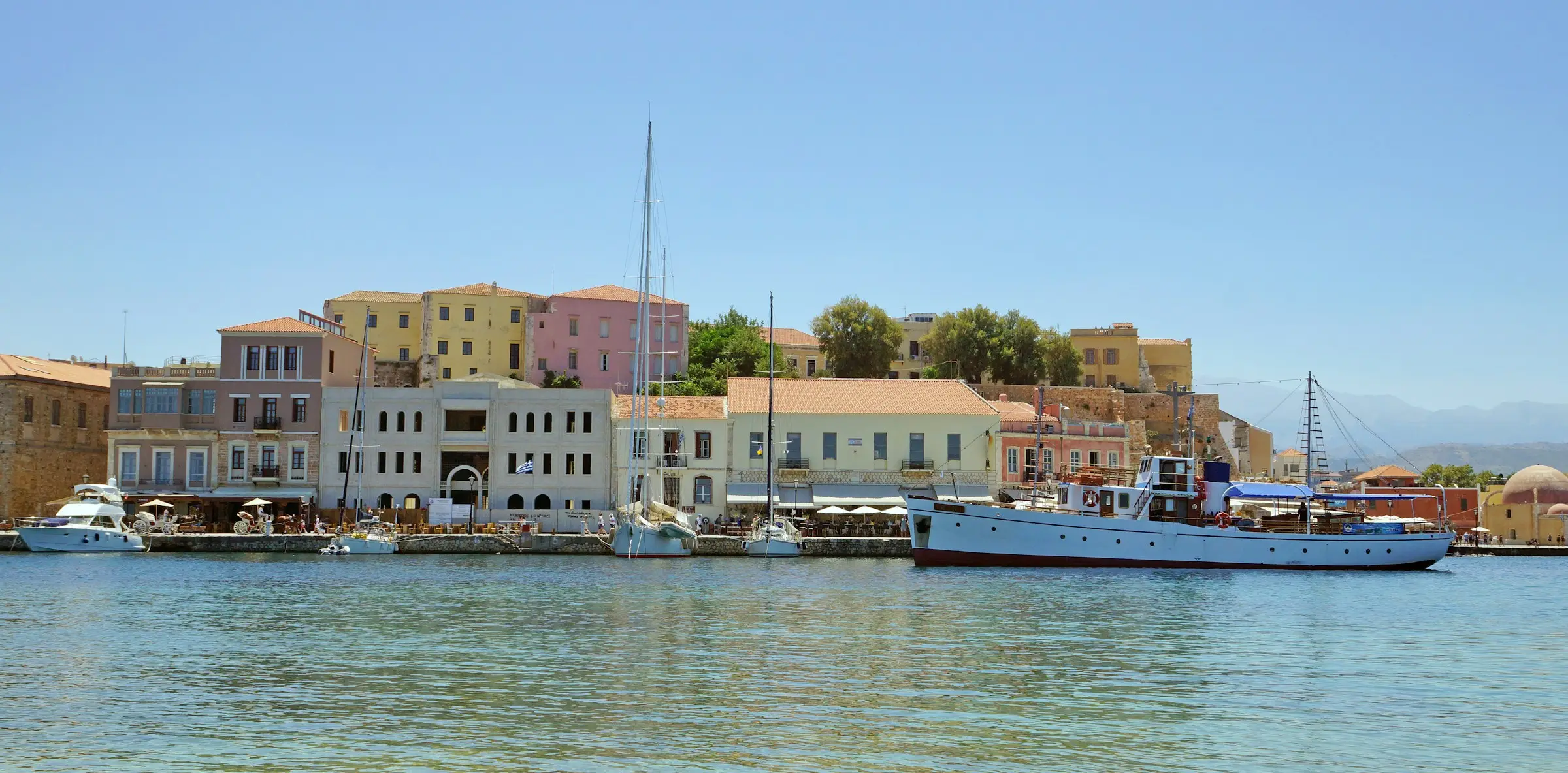 Chania harbour in Crete with colourful waterfront buildings, moored boats and calm blue water